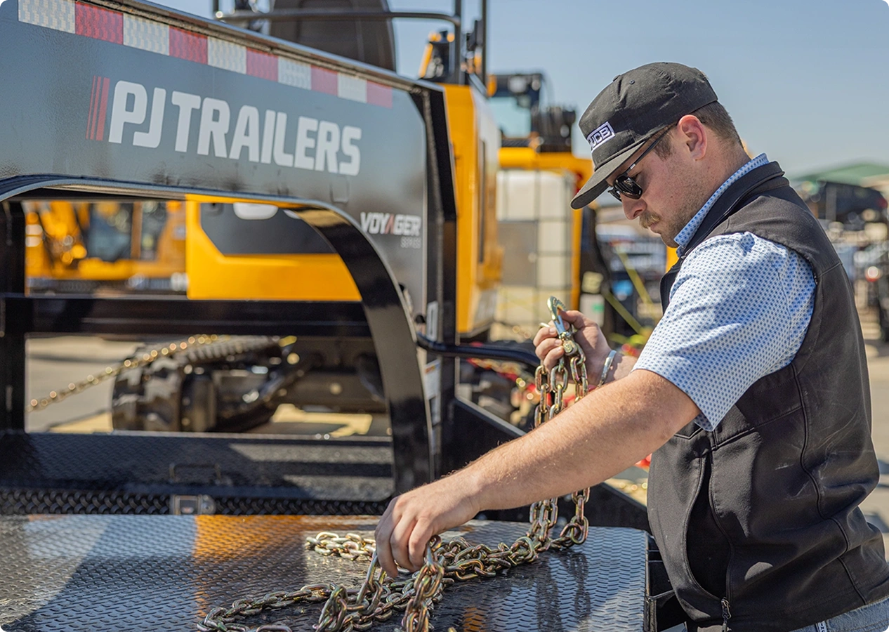 Man securing a load on a PJ Trailer.